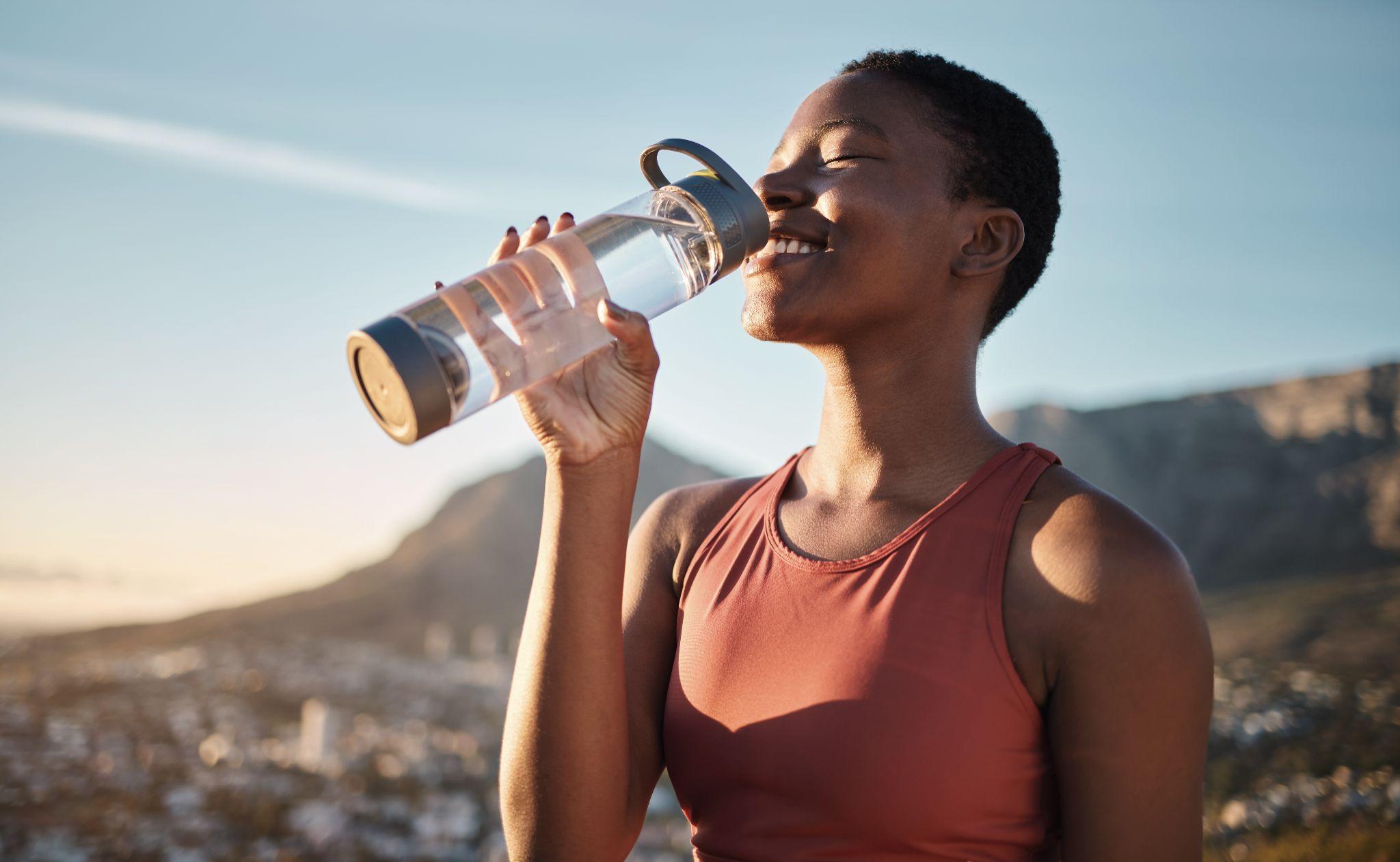 Black woman, runner and drinking water for outdoor exercise