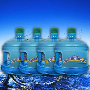 Four large blue water jugs with green caps labeled "Crystal Premium"—perfect for any bottle plan—are lined up in front of a serene blue water and sky background, highlighting the refreshing purity of spring water.